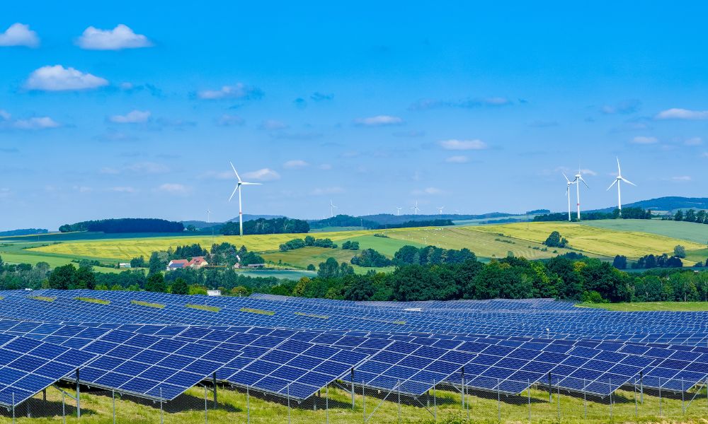 Güneş panelleri ve rüzgar türbinlerinin bulunduğu bir alanda yeşil enerji üretimi.