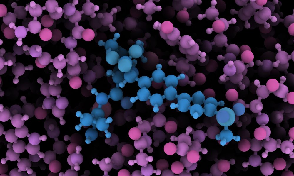 Siyah bir arka plan üzerinde çubuklarla birbirine bağlı mavi, mor ve pembe kürelerden oluşan renkli bir moleküler yapı, karmaşık bir kimyasal bileşikteki atomları ve bağları göstermektedir. Peki bu bağlamda bir inhibitör nedir?